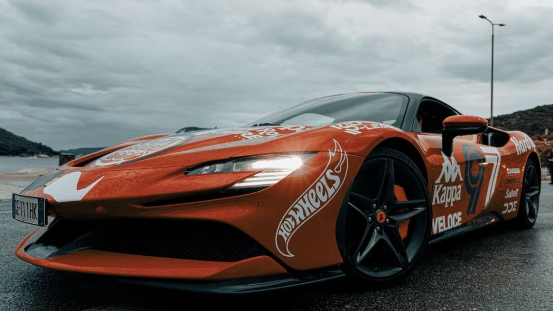 Dynamic shot of an electric sports car adorned with decals on a rainy day in Budva, Montenegro.