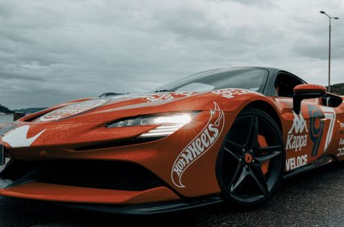 Dynamic shot of an electric sports car adorned with decals on a rainy day in Budva, Montenegro.